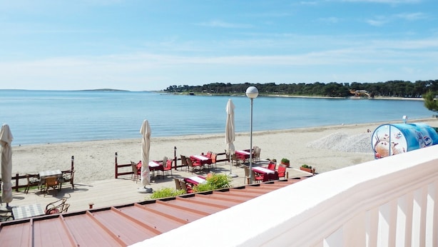 A seaside restaurant with outdoor seating overlooking the beach and water. - Apartments Idila (Medulin)