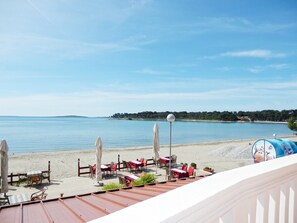 A seaside restaurant with outdoor seating overlooking the beach and water. - Apartments Idila (Medulin)