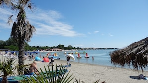 A beach with palm trees, umbrellas, and a police car. - Apartments Idila (Medulin)