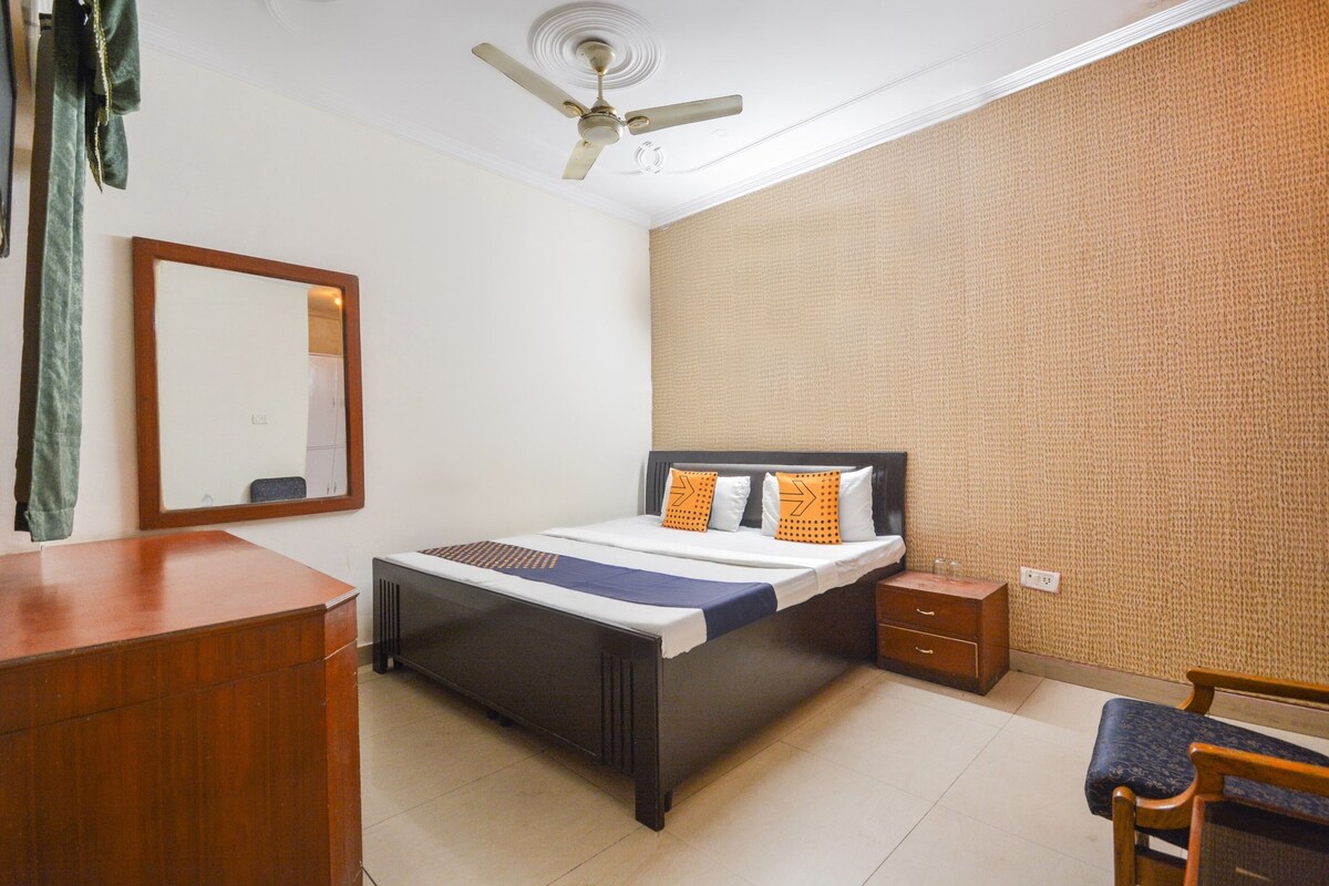 A bedroom with a bed, a nightstand, a dresser, a chair, a ceiling fan, and a mirror.