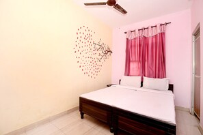 A bedroom with a bed, a ceiling fan, a wall decoration, and a window with curtains. - SPOT ON 37127 Primeland (Mohali)