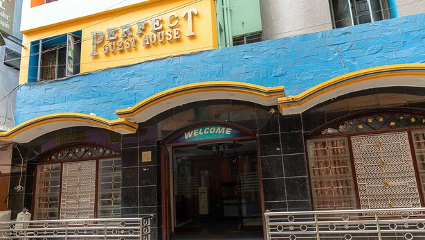 Un edificio con un cartel que dice "Perfect Guest House" y un letrero de "Bienvenida" en la entrada.
