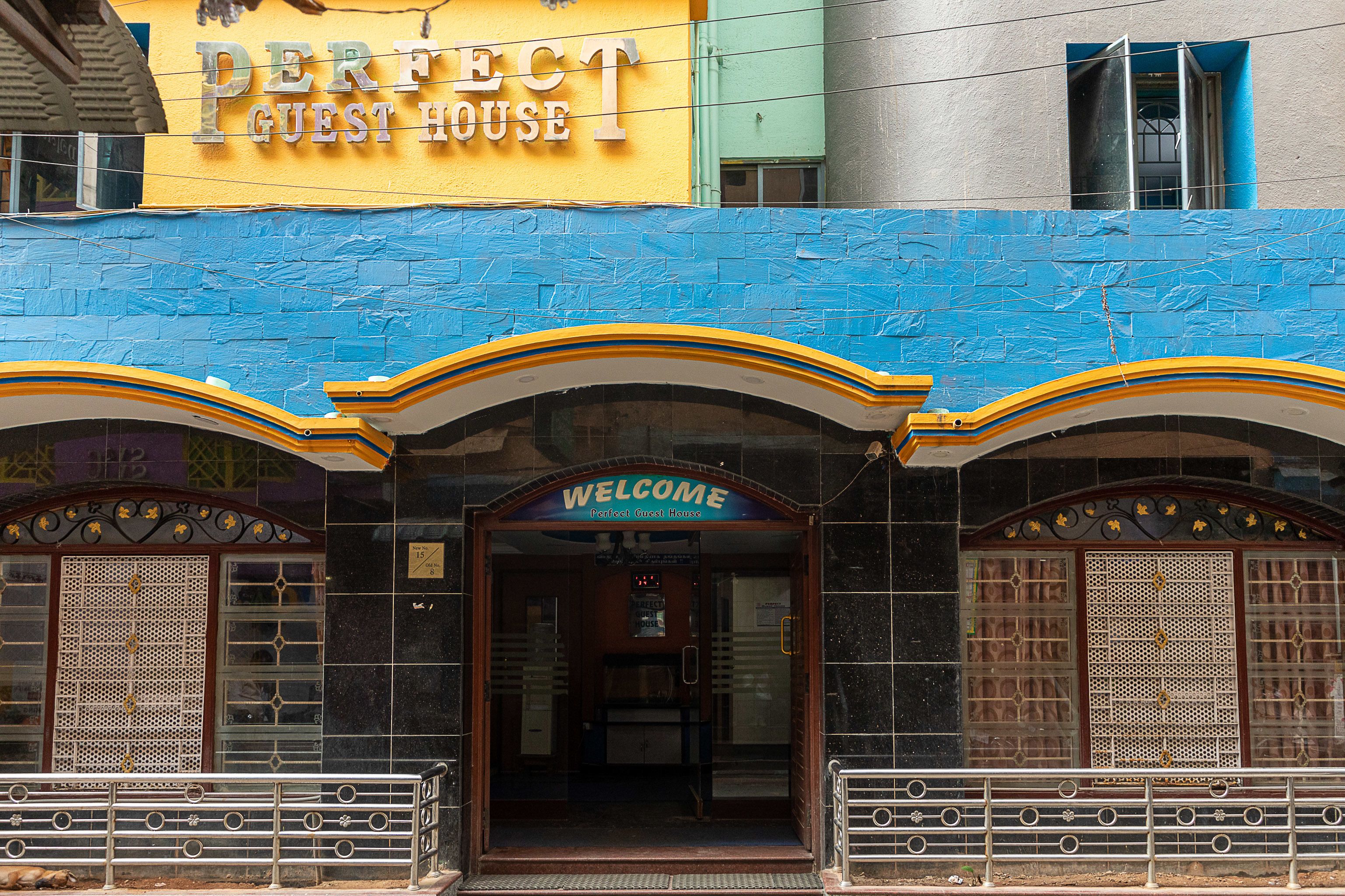 A building with a sign reading "Perfect Guest House" and a "Welcome" sign above the entrance.