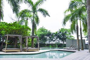 A pool area with lounge chairs and a covered seating area surrounded by palm trees. - OHO Suites KLCC Setia Sky (Kuala Lumpur)