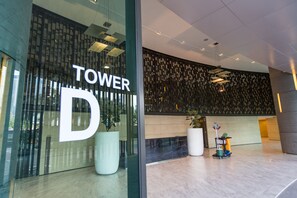 A modern hotel lobby with a large glass entrance, a sign reading "TOWER D", and potted plants. - OHO Suites KLCC Setia Sky (Kuala Lumpur)