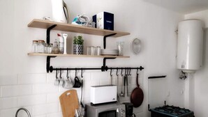 A kitchen with a microwave, toaster, and gas stove. There are shelves above holding jars and a plant. - Résidence Djény T3 (Abidjan)