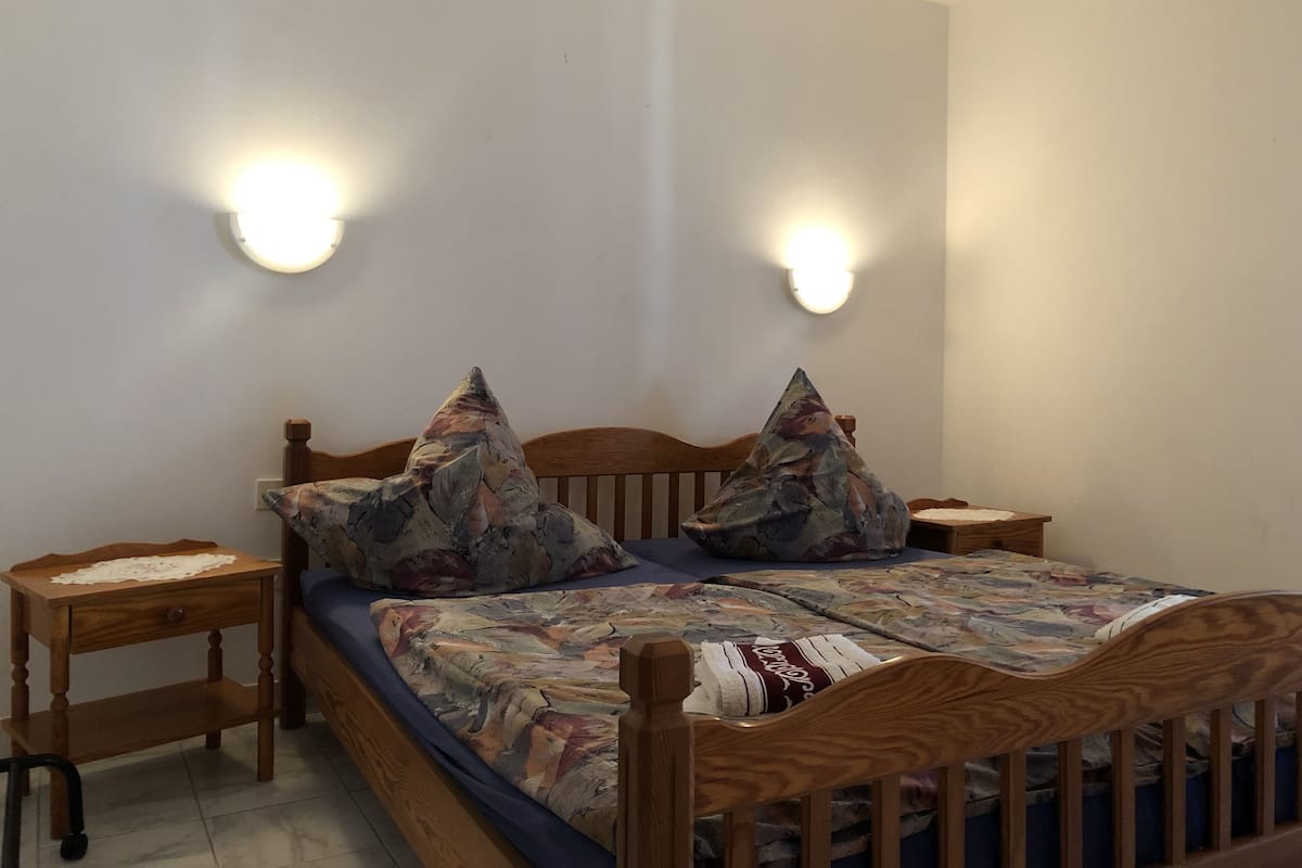 Un dormitorio con una cama de madera, dos mesitas de noche e iluminación en la pared.