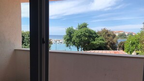 A balcony with a view of a marina, trees, and buildings across the water. - Apartments La Playa (Medulin)