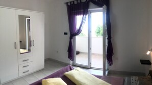 A bedroom with a bed, a wardrobe, and a sliding glass door to a balcony. - Apartments La Playa (Medulin)