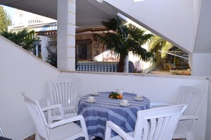 A patio with a round table, white chairs, and a blue patterned tablecloth. - Apartments La Playa (Medulin)