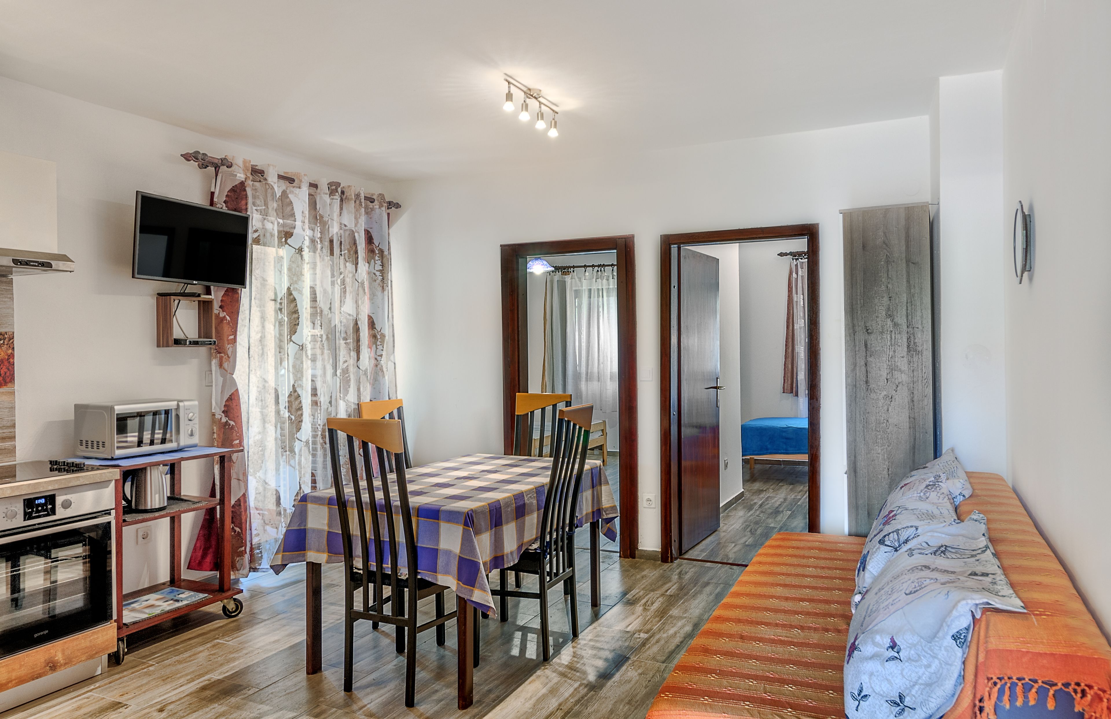 Un espace de vie compact comprenant un coin repas, une kitchenette et un lit.