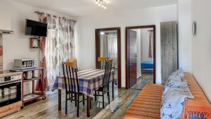 Un espace de vie compact comprenant un coin repas, une kitchenette et un lit.