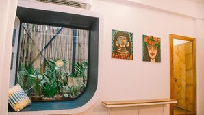 Une pièce dotée d’une grande fenêtre, d’un banc et de deux tableaux accrochés au mur.