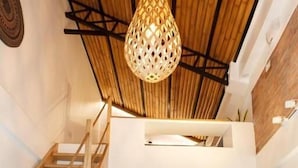 Une pièce de style loft avec un escalier en bois, un luminaire suspendu et un petit coin repas.