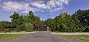 A parking lot with a gated entrance, surrounded by dense greenery and trees.