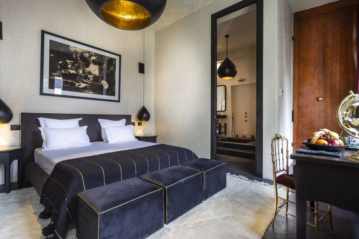 A modern hotel room with a large bed, a desk, and a mirror.