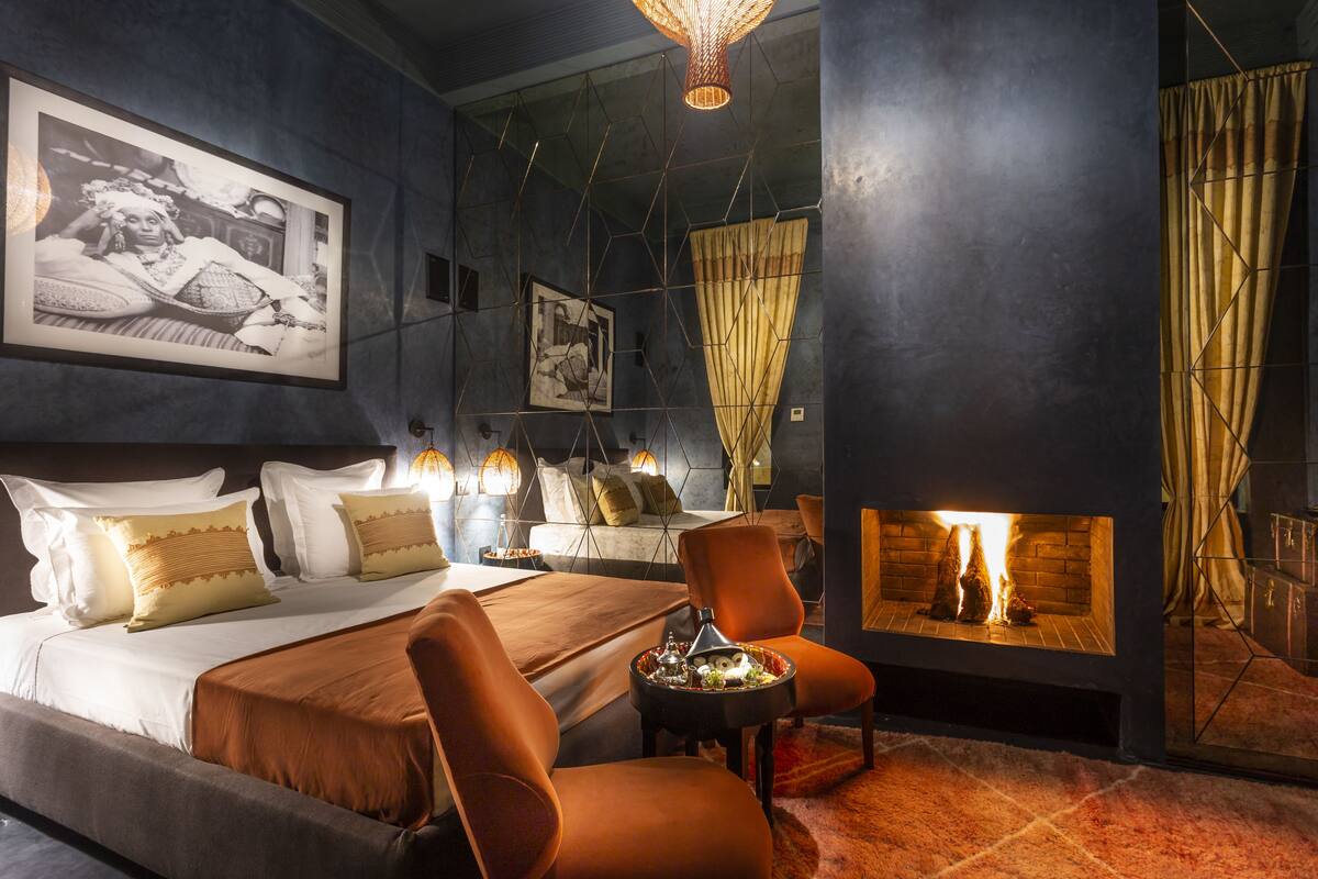 A modern bedroom with a large bed, a fireplace, and a cozy seating area.