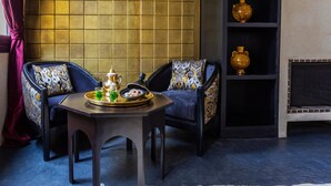A room with two chairs, a small table with a tray of drinks, and a shelf with decorative vases. - Riad Tajania (Marrakech)