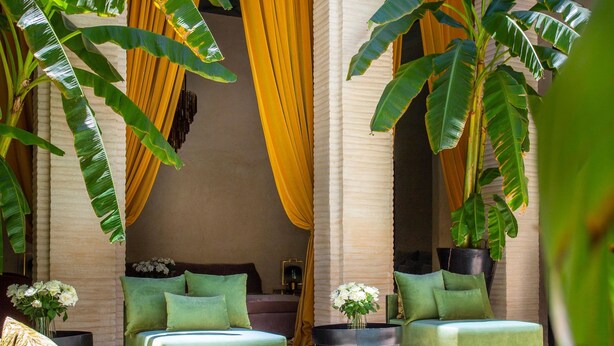 A poolside area with a seating arrangement, a pool, and tropical plants. - Riad Tajania (Marrakech)