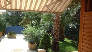 An outdoor patio with a round table and chairs, surrounded by potted plants and a palm tree. - T2 MEZZANINE + TERRACE SAINT CYPRIEN BEACH (Saint-Cyprien Plage)