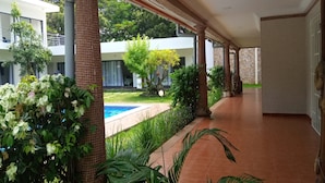A covered corridor with a pool and greenery in the background. - Résidence Akwaba T7 (Abidjan)