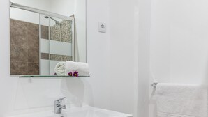 Une salle de bain moderne avec un lavabo blanc, un miroir et un porte-serviettes.