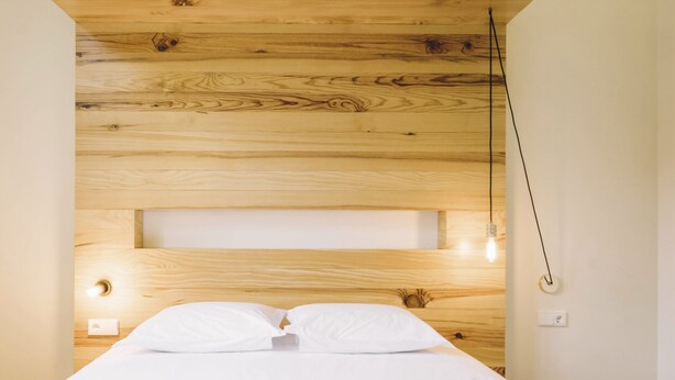 A bedroom with a wooden headboard, a bed with white bedding, and a single bedside lamp. - ORM- Saraiva de Carvalho apartments (Porto)