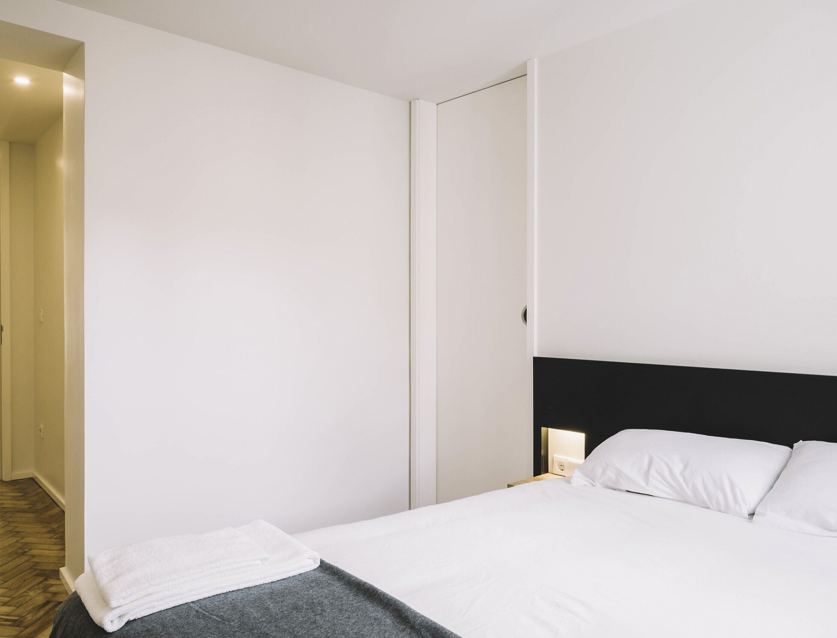 Una camera d'albergo con un letto, un comodino e una porta.