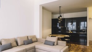 A modern living room with a beige sectional sofa, a round dining table, and a kitchen in the background. - ORM- Saraiva de Carvalho apartments (Porto)