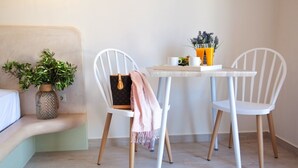 Une petite pièce agréable, avec un canapé blanc, deux fauteuils blancs, une petite table sur laquelle se trouve un verre de jus d’orange et une plante en pot.