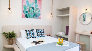 Une chambre à coucher moderne avec un grand lit, un tableau représentant un cactus et une table de chevet agrémentée d’une plante.