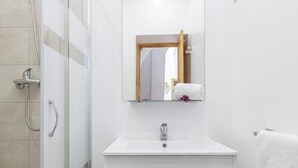 Une salle de bain avec une douche, un lavabo et un miroir.