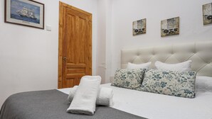 Une chambre avec un grand lit, une porte en bois et trois œuvres d’art accrochées au mur.
