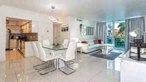 Ein modernes Wohnzimmer mit einem Glastisch, weißen Sofas und Blick ins Freie.