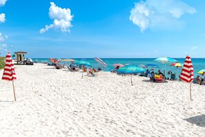 Une plage avec des parasols, des chaises longues et un poste de surveillance pour les sauveteurs.