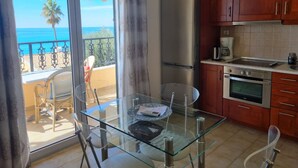 A kitchen with a glass table, stainless steel appliances, and wooden cabinets. - Corfu Island Apartment 40 (Corfu)