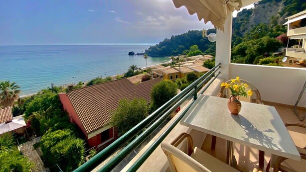 A balcony with a view of the sea, a table with a vase, and a chair. - Corfu Island Apartment 86 (Corfu)