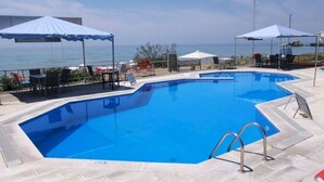 A swimming pool with a view of the sea, surrounded by lounge chairs and umbrellas. - Corfu Island Apartment 86 (Corfu)