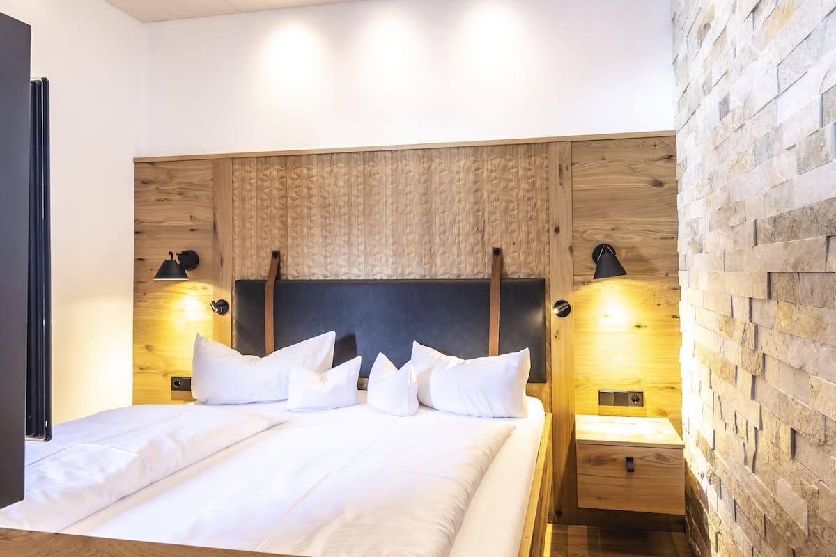 A modern bedroom with a wooden headboard, white bedding, and bedside lamps.
