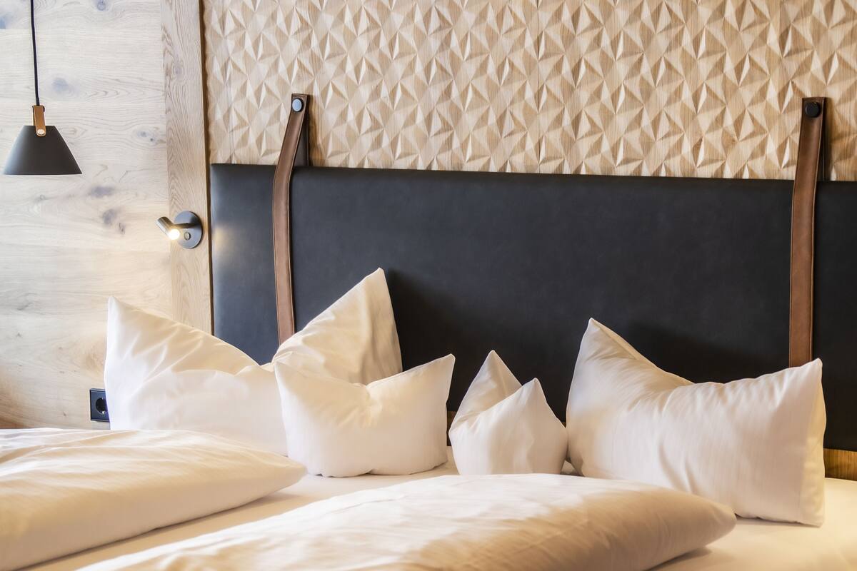A bed with white bedding and a headboard with a geometric pattern.
