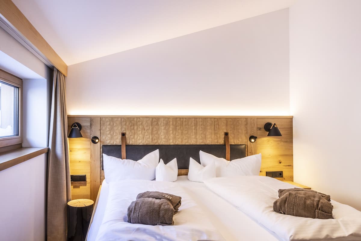A hotel room with a wooden headboard, white bedding, and two bedside lamps.