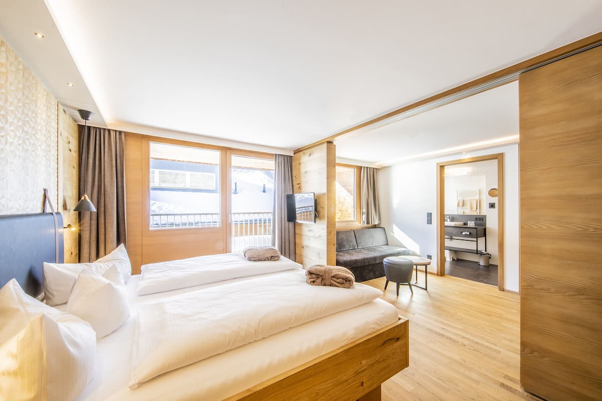 A modern hotel room with a large bed, a desk, and a balcony.