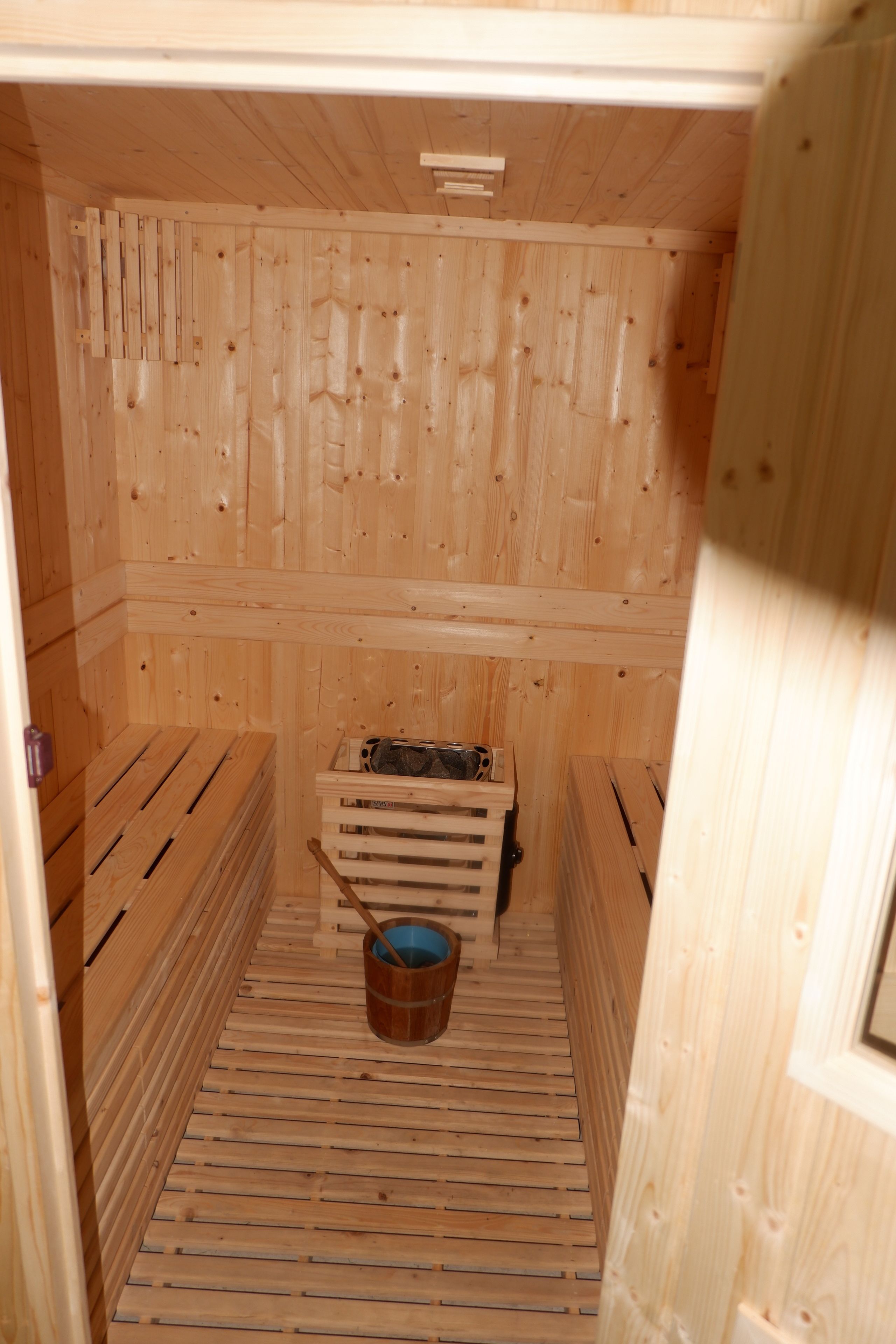 A wooden sauna with benches and a bucket.