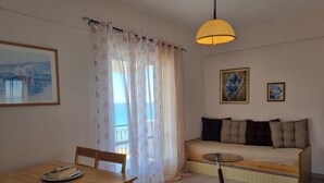 Um quarto aconchegante com uma mesa de madeira, um sofá com almofadas, uma mesinha redonda e um abajur pendente.