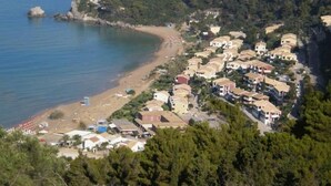 Eine Wohngegend an der Küste mit Häusern direkt am Strand und einer kleinen Gebäudegruppe im Vordergrund.