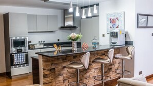 Een moderne keuken met een centraal eiland, barkrukken en ingebouwde apparatuur.