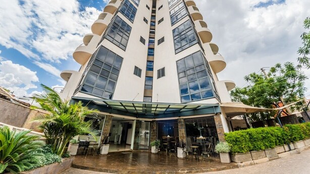 Een modern meerlaags hotel met een centraal atrium, grote ramen en een terras.