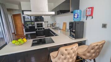 Una cocina moderna con una isla central, dos taburetes de bar, una cafetera y un dispensador de agua.