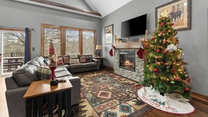 A cozy living room with a fireplace, a Christmas tree, and a large window. - Pool&SplashPad Hot Tub PoolTable, Foosball, Lake, Shows, Golf, Shop, FUN (Hollister)