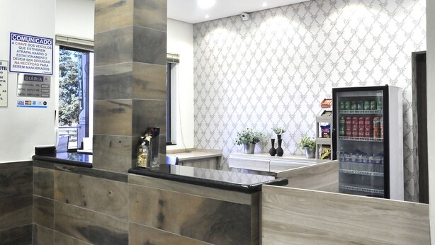 Zona de recepción con mostrador de mármol, máquina expendedora y pared decorada.